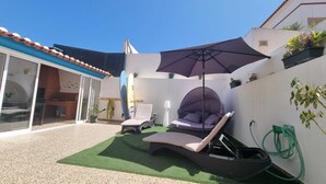 A patio with a lounge chair, a swing chair, and a large umbrella. - Baleal Paradise Inn (Peniche)