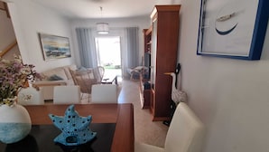 A living room with a sofa, a dining table, a decorative starfish, and a wooden cabinet. - Baleal Paradise Inn (Peniche)