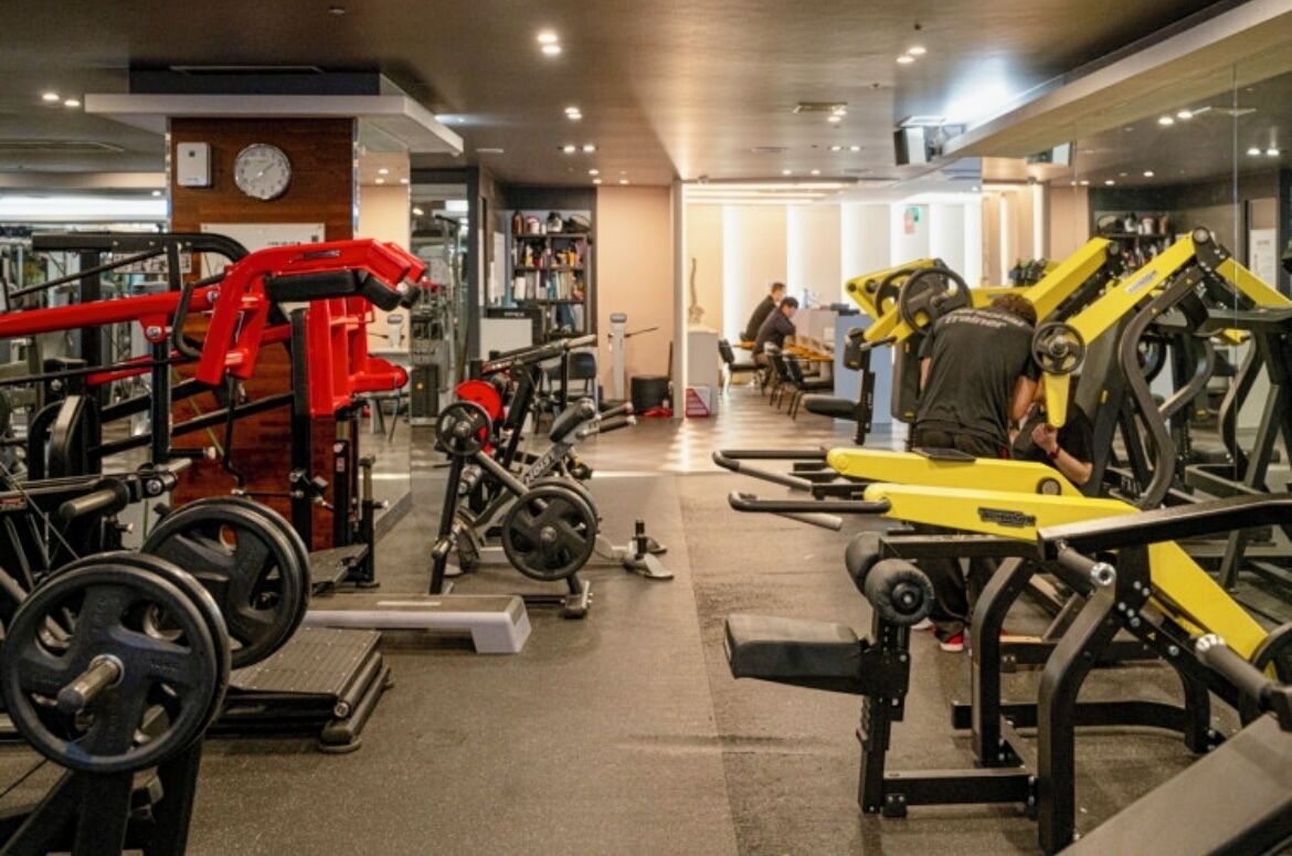 Uma academia com diversos equipamentos de exercício, incluindo máquinas de peso e pesos livres.