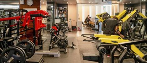Uma academia com diversos equipamentos de exercício, incluindo máquinas de peso e pesos livres.