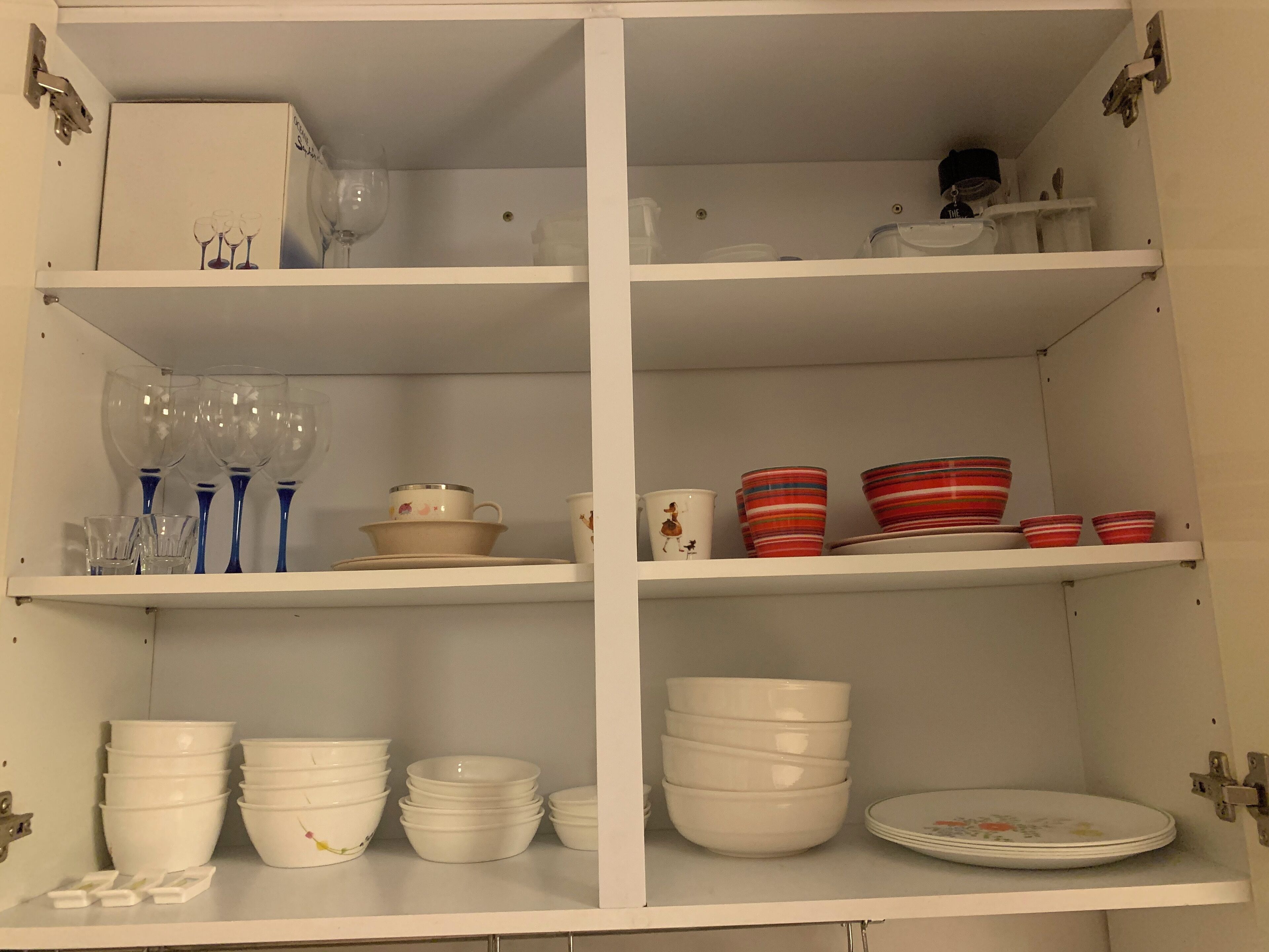 Ein weißer Schrank mit mehreren Regalen, gefüllt mit verschiedenen Küchenutensilien.