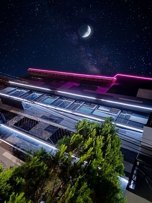 Un edificio moderno con fachada de vidrio y una franja de neón rosa.