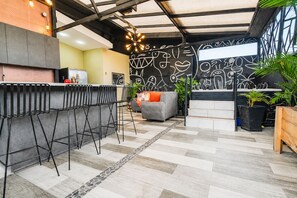 Una cocina moderna con barra, zona de estar con sofá y sillas, y una pared decorativa con diseños abstractos.