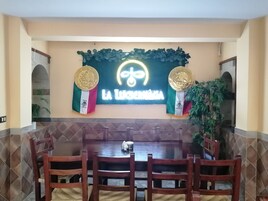 Un restaurante con una amplia mesa de comedor, sillas y un letrero de neón arriba.