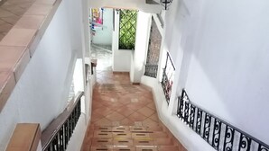 A staircase with brown tiles and black railings, leading to a door with a metal gate. - Hotel San Fernando (Ciudad Valles)