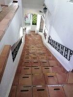 Una escalera con baldosas marrones y barandillas negras que conduce a una puerta con reja de metal.