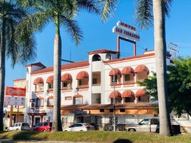 Un hotel de varios pisos con fachada roja y blanca, múltiples balcones y un letrero destacado que dice 'HOTEL SAN FERNANDO'.
