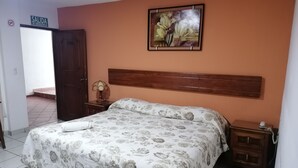 A bedroom with a bed, a nightstand, a painting, and a door labeled "SALIDA DE EMERGENCIA". - Hotel San Fernando (Ciudad Valles)