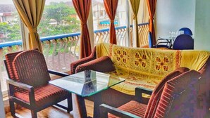 A balcony with a sofa and chairs, a glass table, and a view of the city. - Charming 3-bedroom apartment with AC in Goa, 500 mtrs from Zalor Beach, Goa (Goa)