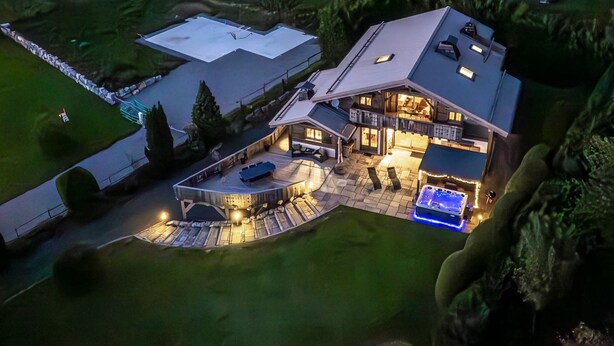 Una casa grande y moderna con un patio amplio, un jacuzzi y un interior bien iluminado.