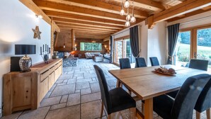 Interior de madera con zona de comedor, suelo de piedra y chimenea.