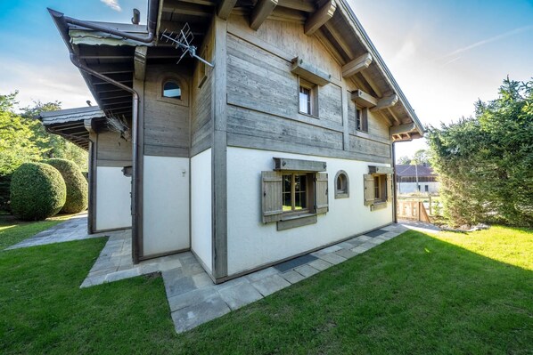 Une maison en bois à deux étages, avec un toit en pente, un petit porche à l’avant et une pelouse bien entretenue.