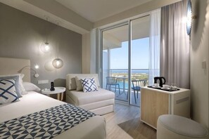 Una habitación de hotel moderna con cama, sofá, una mesita con una tetera y un balcón con vistas.