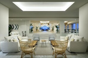 A modern lobby with a central seating area, a reception desk, and a view of the building's entrance. - Palladium Hotel Menorca (Area Metropolitana de Mao)