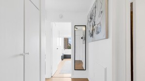A hallway with white walls, a wooden floor, and a large mirror on the right. - Downtown Montreal Horizon W/ Balcony | 1BR Queen Bed, Sofa Bed, Parking & Gym (Montreal)