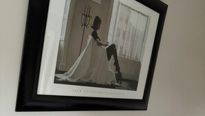 Ein gerahmtes Foto einer Frau in einem weißen Kleid an einer Wand.