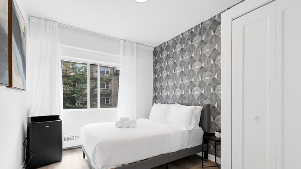 Een moderne slaapkamer met een bed, een raam en een radiator.