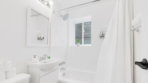 Een moderne badkamer met een witte wastafel, spiegel en bad.