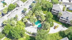 An aerial view of a residential area with a swimming pool surrounded by palm trees and houses. - Lovely 2-bedroom condo with pools and AC in amazing St. George (St. George)