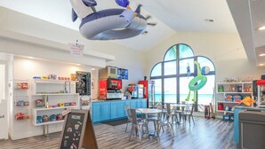 A children's play area with a large window, a Coca-Cola refrigerator, and a menu board. - Lovely 2-bedroom condo with pools and AC in amazing St. George (St. George)