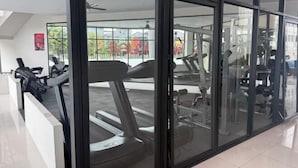 Une salle de sport équipée de matériel d’exercice, dotée de grandes fenêtres et offrant une vue sur l’extérieur.