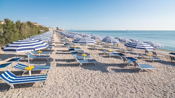 A beach with rows of striped beach umbrellas and lounge chairs. - Le Mimose Family Camping Village Apartment Superior for 6 people (Porto Sant'Elpidio)
