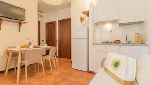 Una cocina compacta con armarios blancos, horno empotrado y comedor con mesa y sillas.