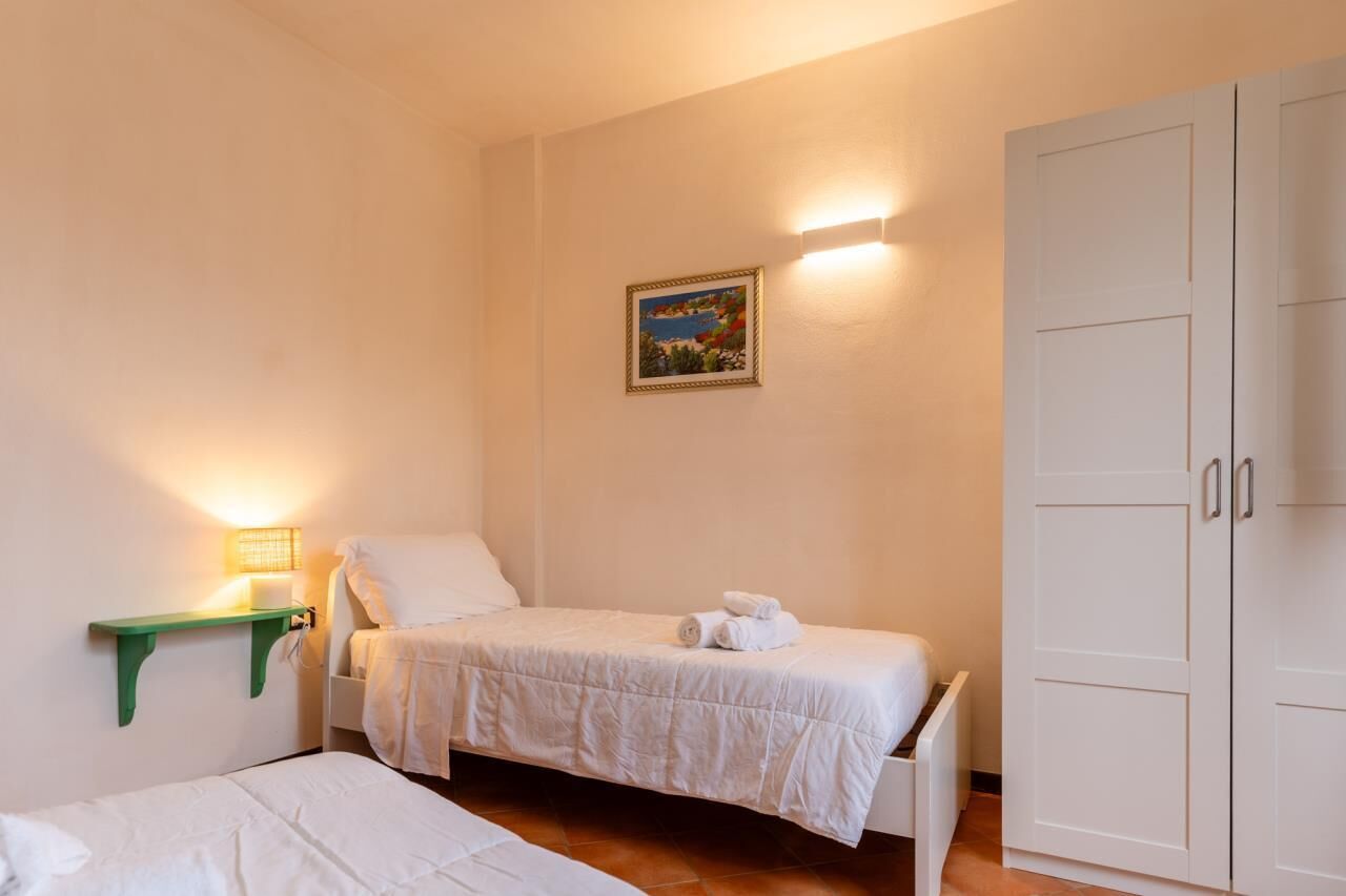 A bedroom with a bed, a nightstand, a wardrobe, and a wall-mounted picture.