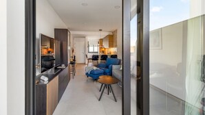 Una cucina moderna con mobili scuri, un'isola centrale e un'area pranzo con sedie blu.