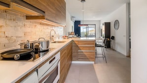 Una cucina moderna con zoccolo in legno, isola centrale e vista su un balcone.