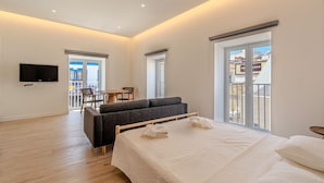 A modern hotel room with a large bed, a sofa, a TV, and a balcony with city views. - Old Town Studio F 150m Praia T nel (Albufeira)