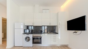 A modern kitchen with white cabinets, a built-in oven, a washing machine, and a flat-screen TV mounted on the wall. - Old Town Studio F 150m Praia T nel (Albufeira)