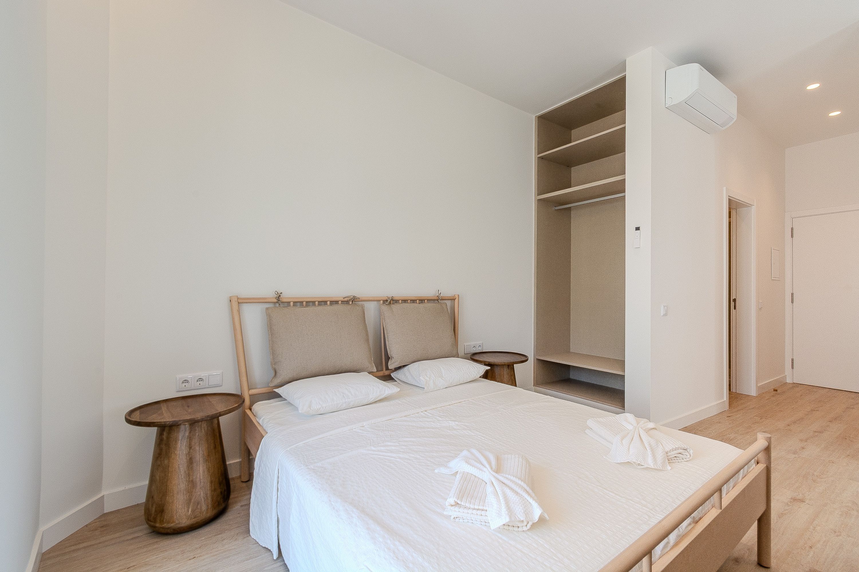 Ein Schlafzimmer mit Bett, Nachttischen, einem Kleiderschrank und einer Klimaanlage.