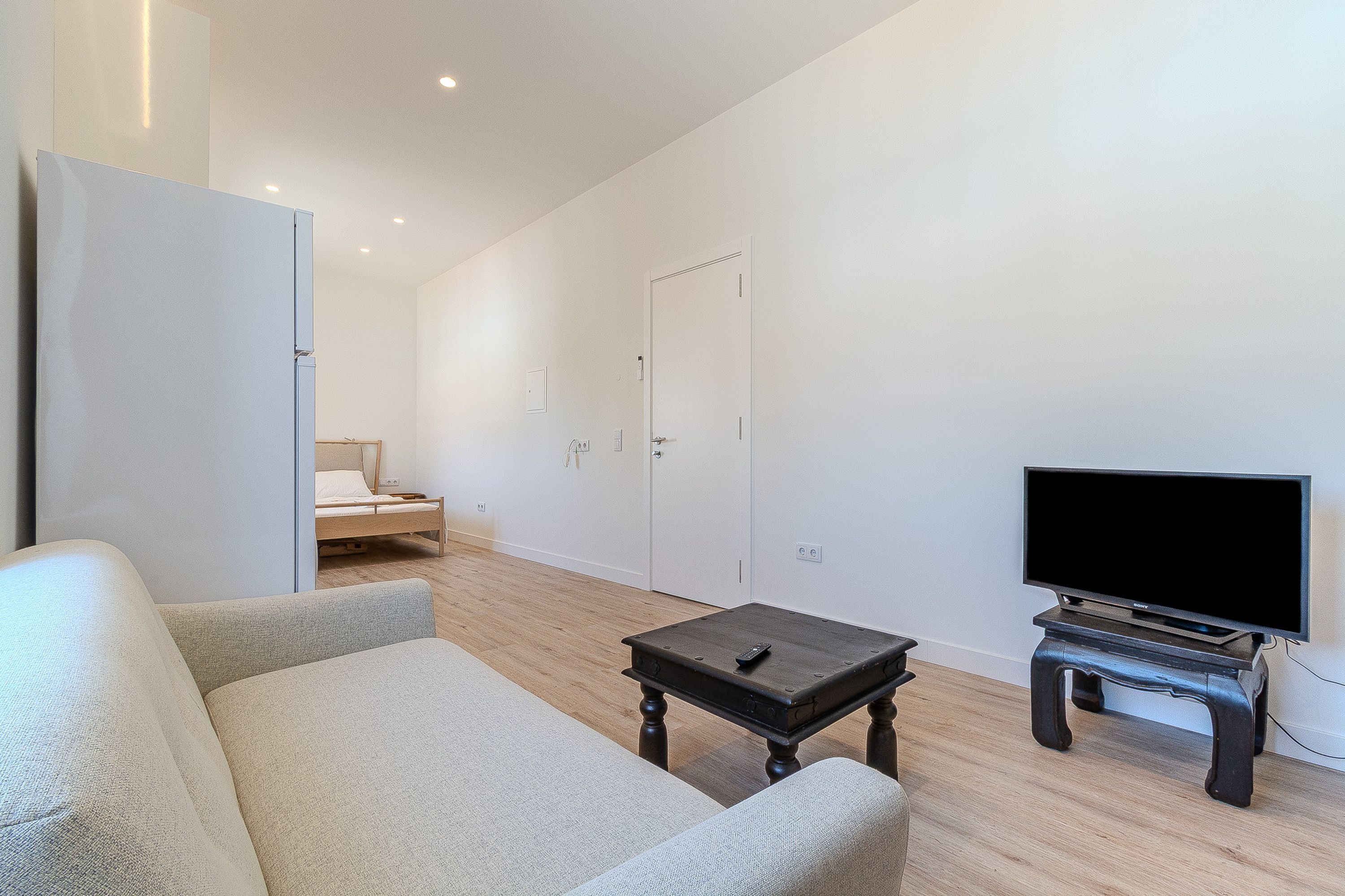 A modern living room with a sofa, a coffee table, and a TV on a stand.