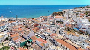A coastal town with white buildings, a clear blue sea, and a small boat in the distance. - Old Town Studio G 150m Praia T nel (Albufeira)