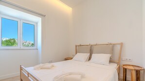A neatly made bed with white linens and towels, a wooden headboard, and a small wooden side table. - Old Town Studio G 150m Praia T nel (Albufeira)