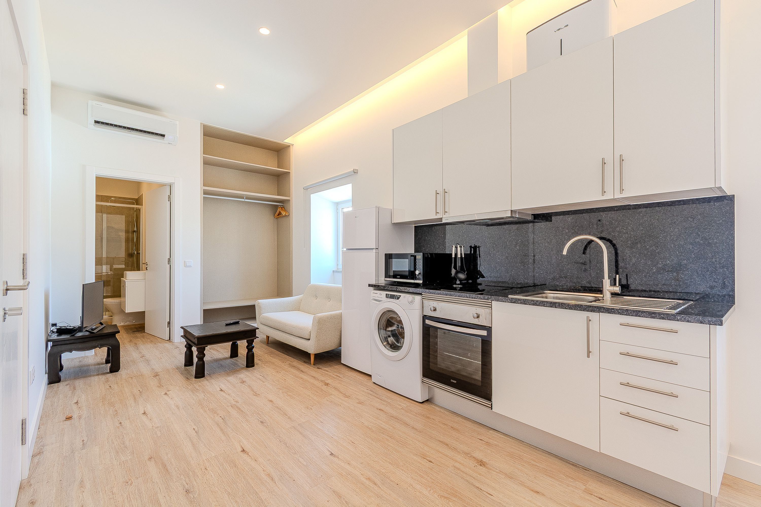 Une cuisine moderne avec des meubles blancs, un lave-linge encastré et un four à micro-ondes.