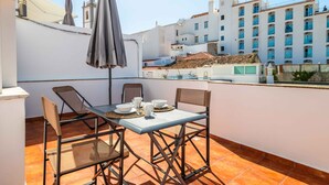 A rooftop terrace with a table set for two, chairs, and a table umbrella. - Downtown Rooftop 1 Bedroom Apartment (Albufeira)