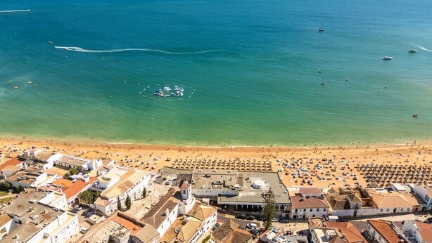 An aerial view of a coastal town with a beach, boats, and buildings. - Downtown Rooftop 1 Bedroom Apartment (Albufeira)