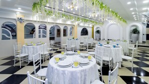 A dining area with round tables, white chairs, and hanging plants. - Hotel Playa Salguero By GEH Suites  (Santa Marta)