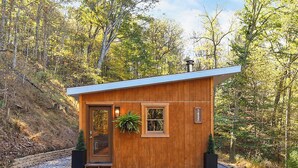 Una pequeña cabaña de madera con techo inclinado, una puerta y una ventana.
