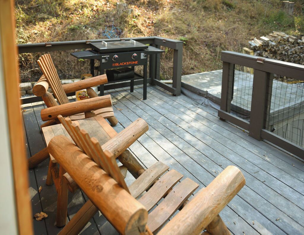 Una terraza de madera con una parrilla y sillas.