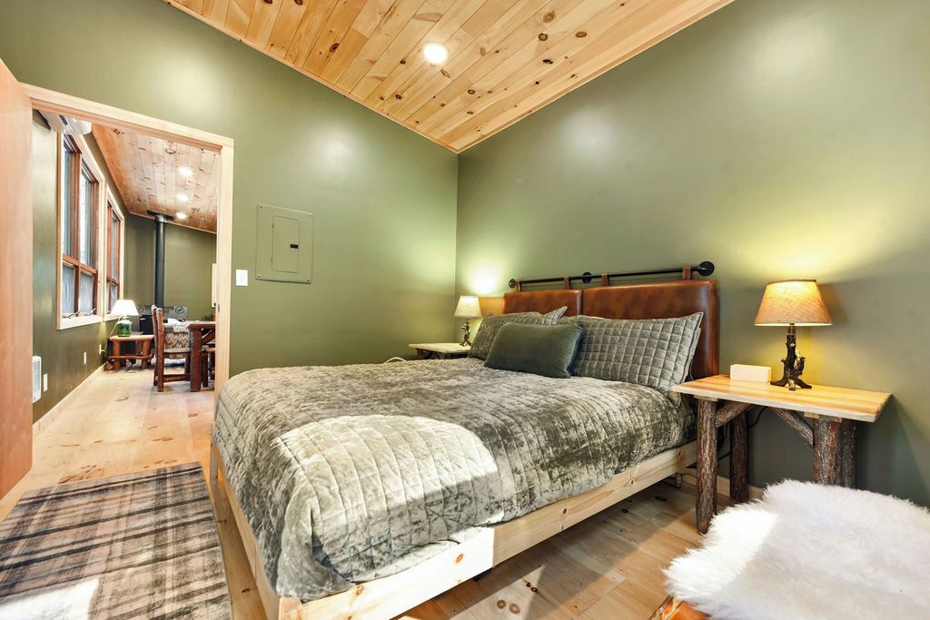 A bedroom with a wooden bed, two bedside tables, a nightstand, a chair, and a lamp.