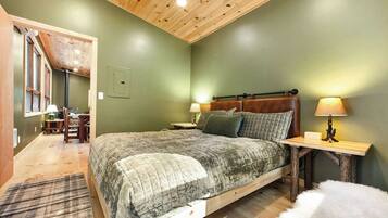 A bedroom with a wooden bed, two bedside tables, a nightstand, a chair, and a lamp.