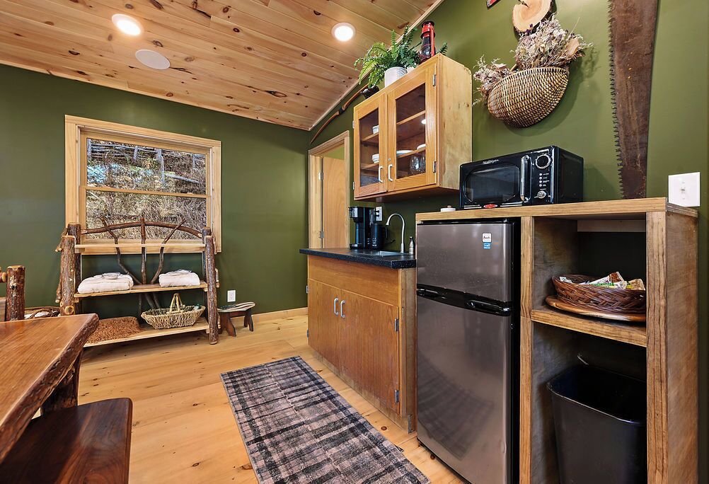 A compact kitchen with wooden cabinets, a built-in microwave, and a stainless steel refrigerator.
