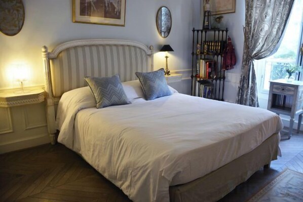Un lit bien fait, avec des oreillers, une table de chevet avec une lampe et une fenêtre avec des rideaux.