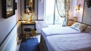 A bedroom with a bed, a desk with a chair, a mirror, and a window with curtains. - Elegant 3 Bedroom Apt Near Eiffel Tower - Alma (Paris)