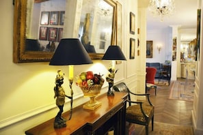 A hallway with a wooden console table, two lamps with black shades, a fruit bowl, and a mirror on the wall. - Elegant 3 Bedroom Apt Near Eiffel Tower - Alma (Paris)