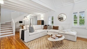 A spacious living room with a white sectional sofa, a coffee table, and a staircase leading to another level. - Spencer House in Leura (Leura)