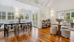 A spacious room with wooden flooring, a dining area with a round table, and a seating arrangement. - Spencer House in Leura (Leura)